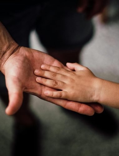 Close-up of a child's hand resting gently on a man's hand, symbolizing love and support.