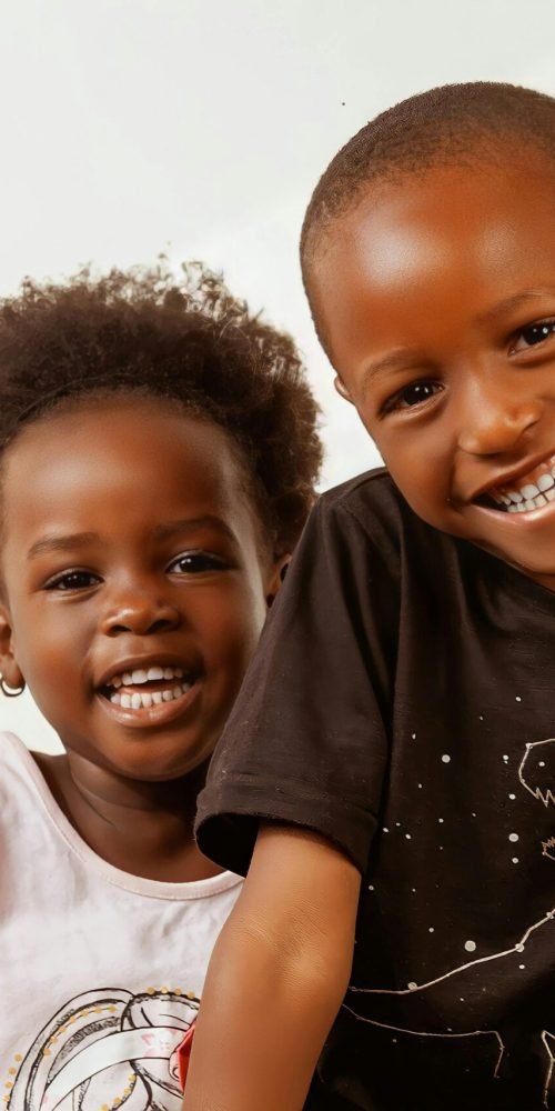 Joyful siblings smiling brightly, showcasing happiness and connection in Kampala, Uganda.