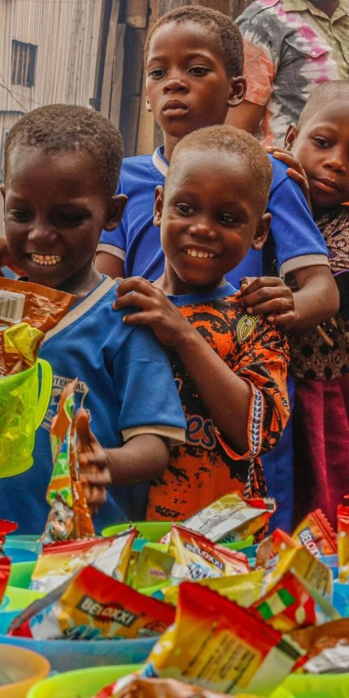Joyful children receiving food supplies from a volunteer in an outdoor setting.